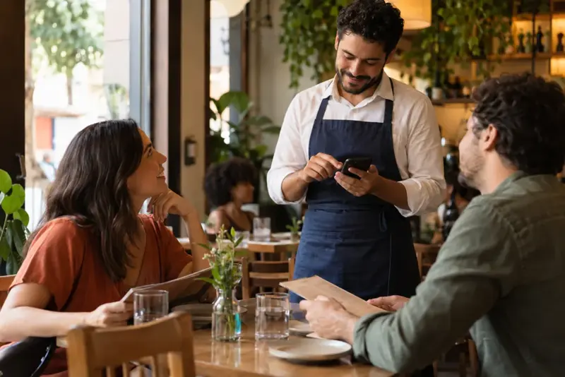 Garçom anotando o pedido dos clientes pelo celular